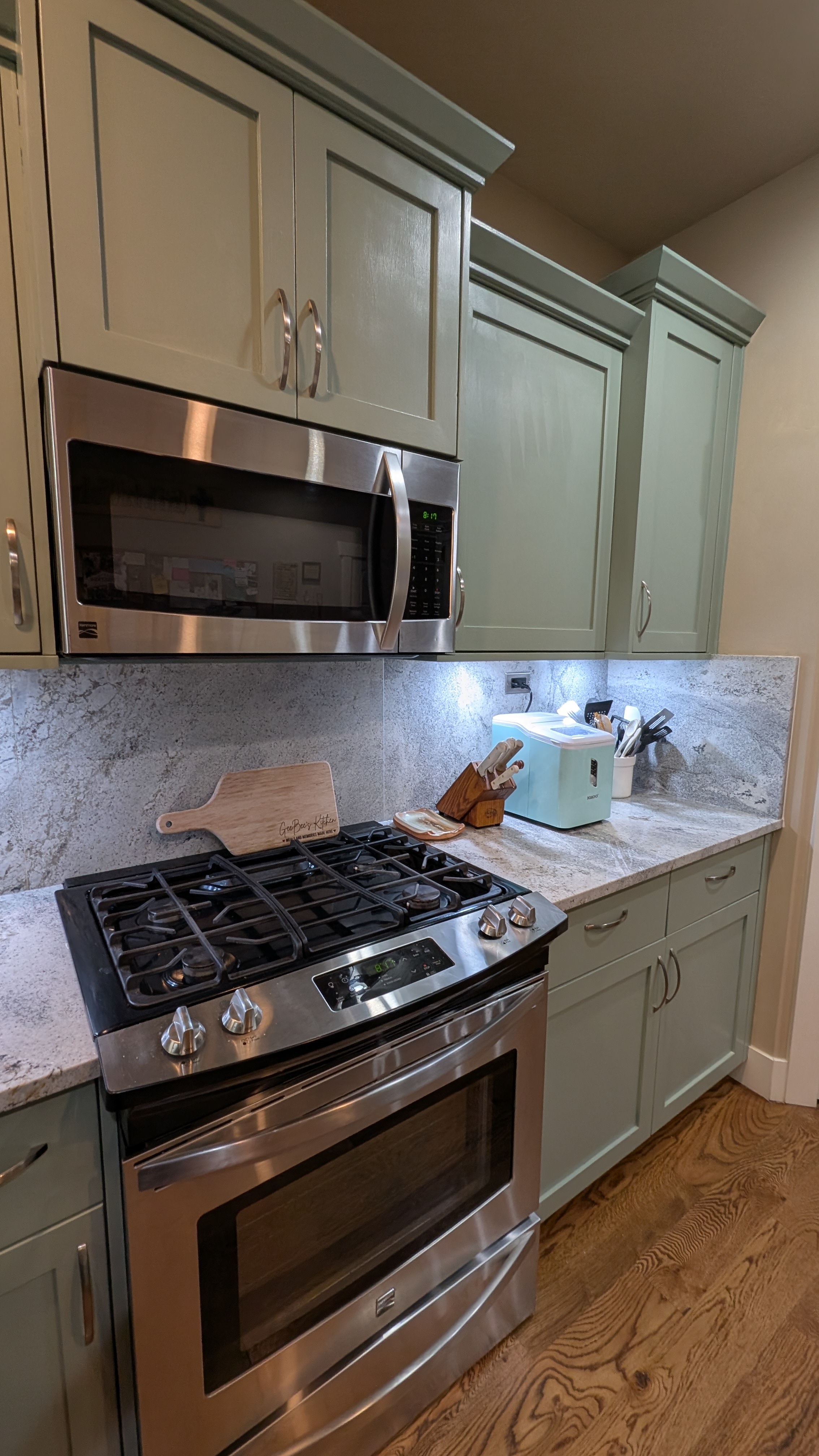 Kitchen with sage-green shaker cabinets, marble-look counters and stainless appliances