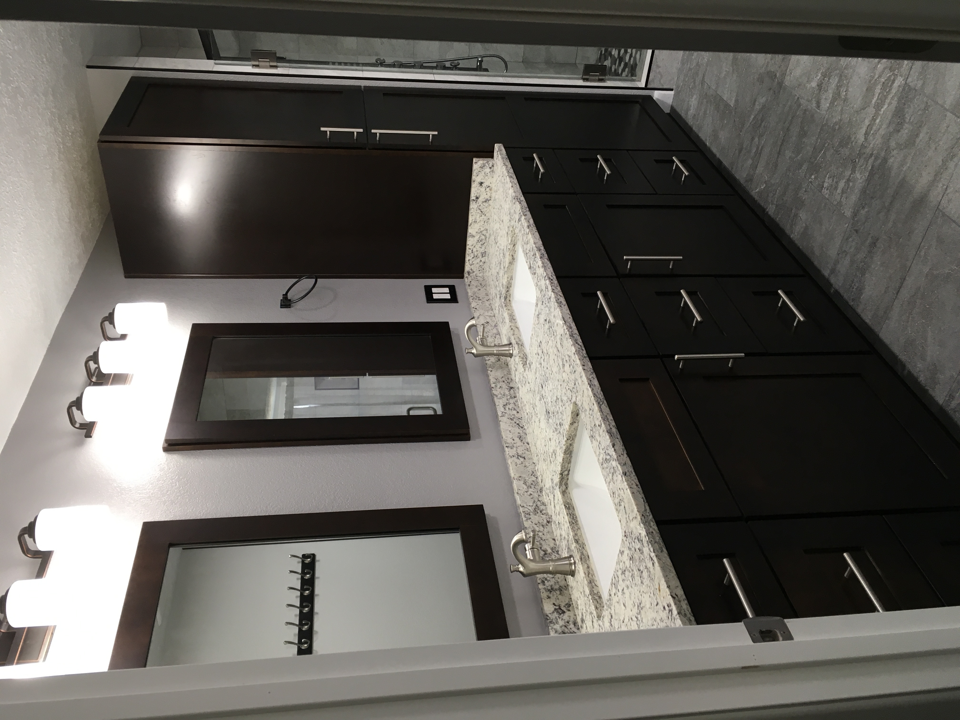 Bathroom with espresso cabinetry, tall linen tower, granite vanity and glass shower