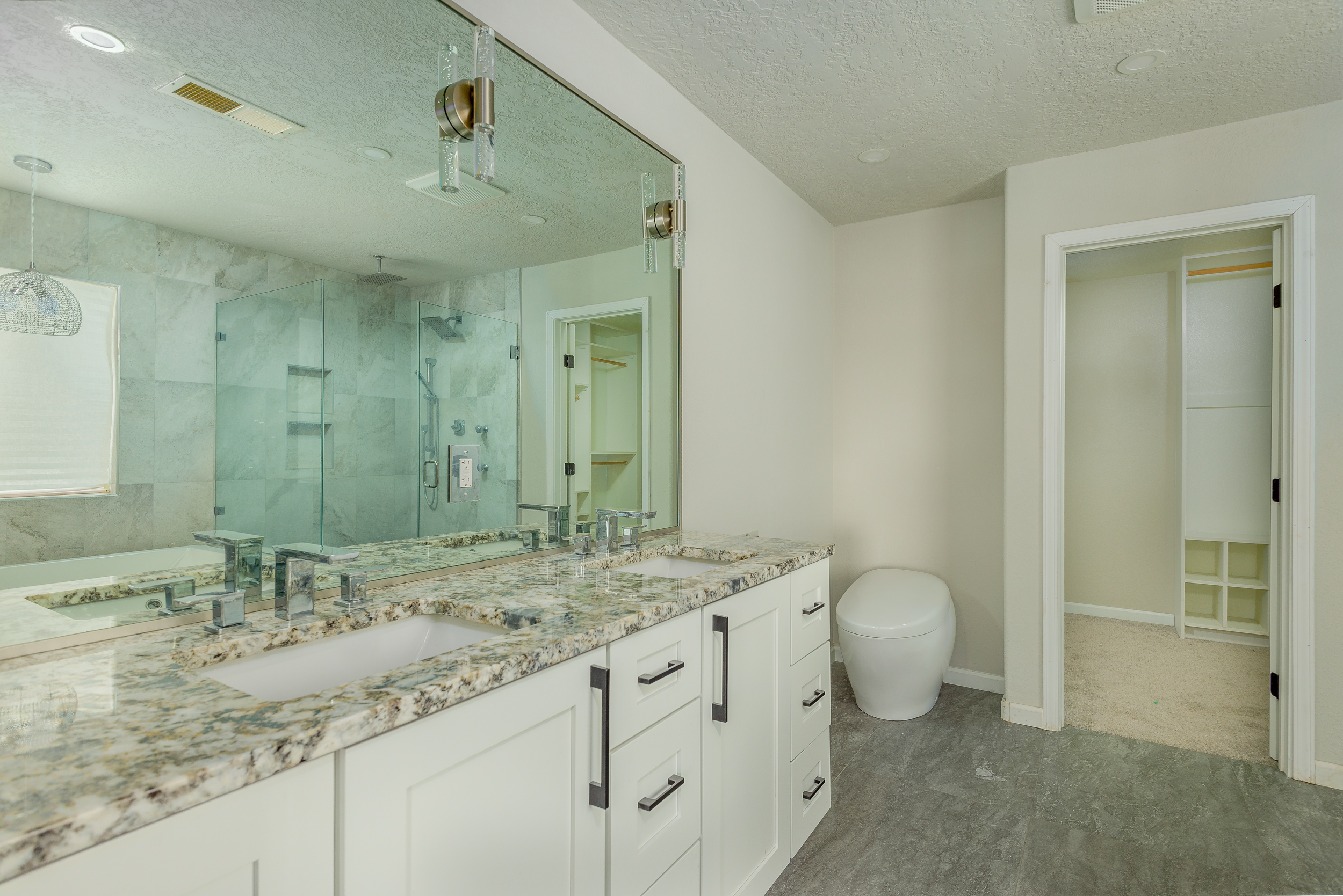 Primary bathroom with granite double vanity, glass shower and soaking tub