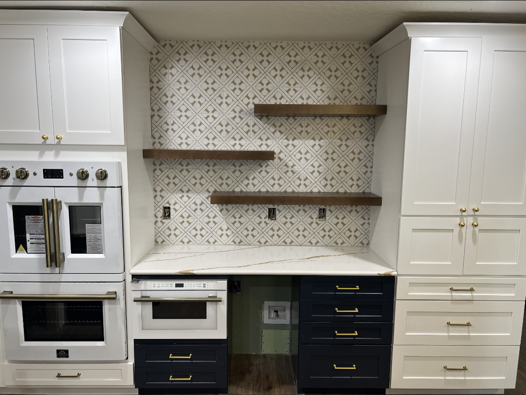 Kitchen with white shaker uppers, navy base cabinets, brass hardware and wood floating shelves