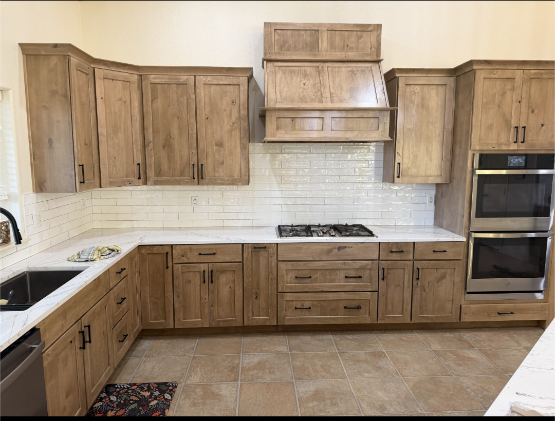 Remodeled kitchen with warm natural wood cabinetry, marble-look quartz countertops and white subway tile backsplash